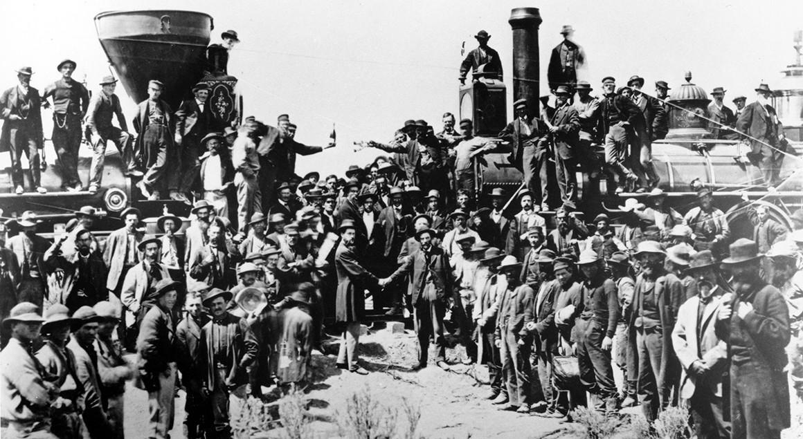 Railroad officials and employees celebrate the completion of the first railroad transcontinental link in Promontory, Utah, on May 10, 1869. The Union Pacific's Locomotive No. 119 (right) and Central Pacific's Jupiter edged forward over the golden spike that marked the joining of the nation by rail. | Andrew J. Russell creator QS:P170,Q4757433 Restoration by Adam Cuerden, East and West Shaking hands at the laying of last rail Union Pacific Railroad - Restoration, marked as public domain, more details on Wikimedia Commons