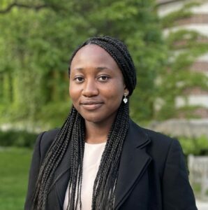 Northeast Maglev Intern Comfort Oshagbemi posing in a suit with trees in the background.