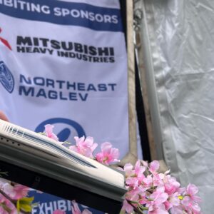 Photograph of a model maglev, dubbed "mini maglev" in front of cherry blossoms.